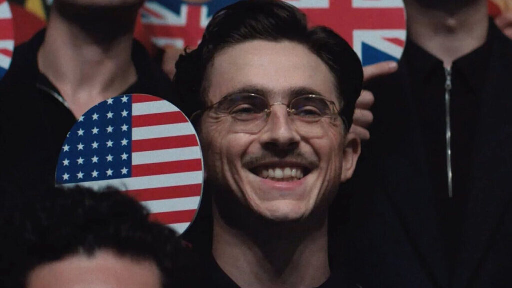 Timothée Chalamet mostrando a cámara una pala de ping pong con la bandera estadounidense en 'Marty Supreme'.